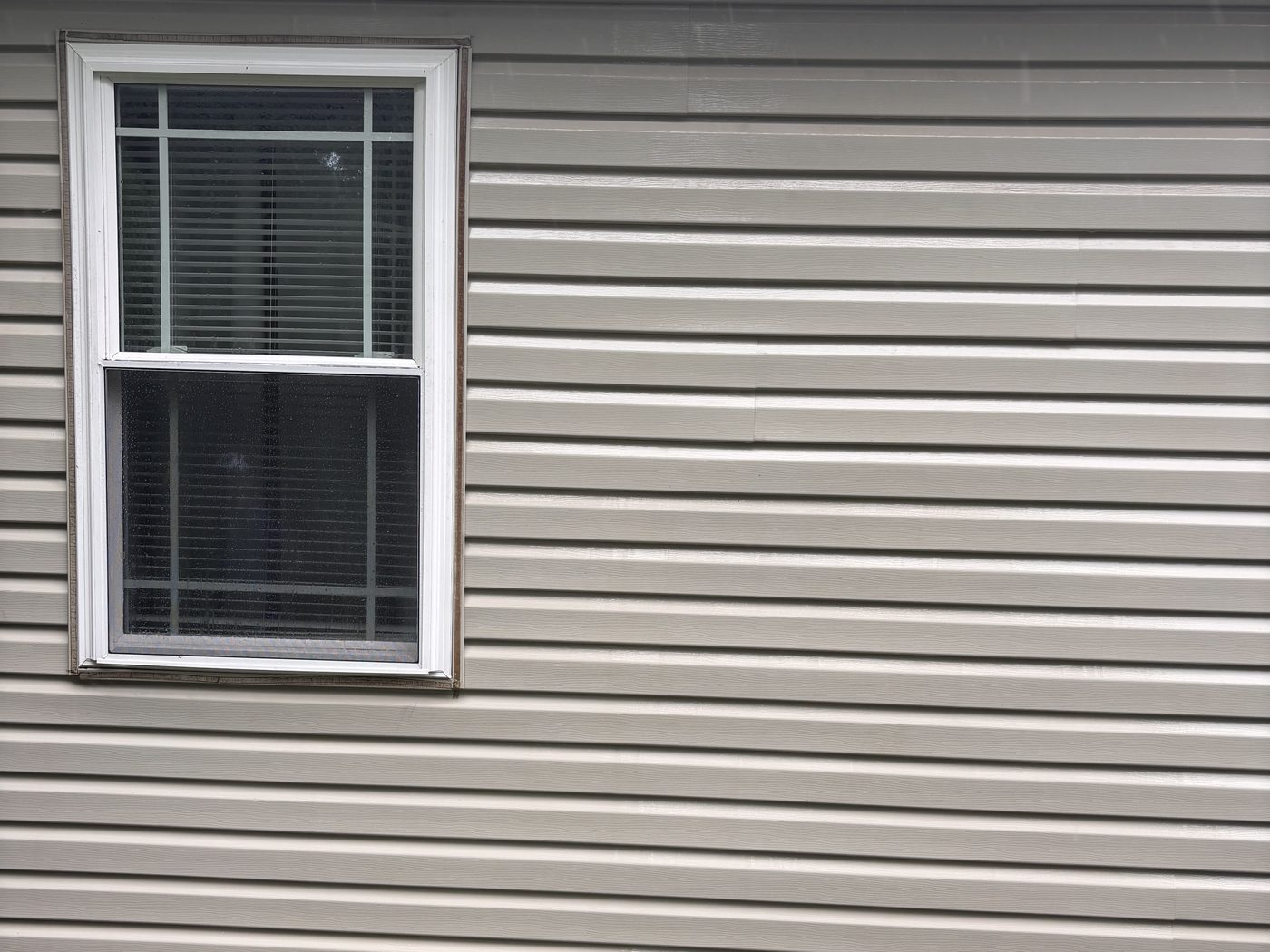 The same siding after a soft wash, with clean, even tan panels