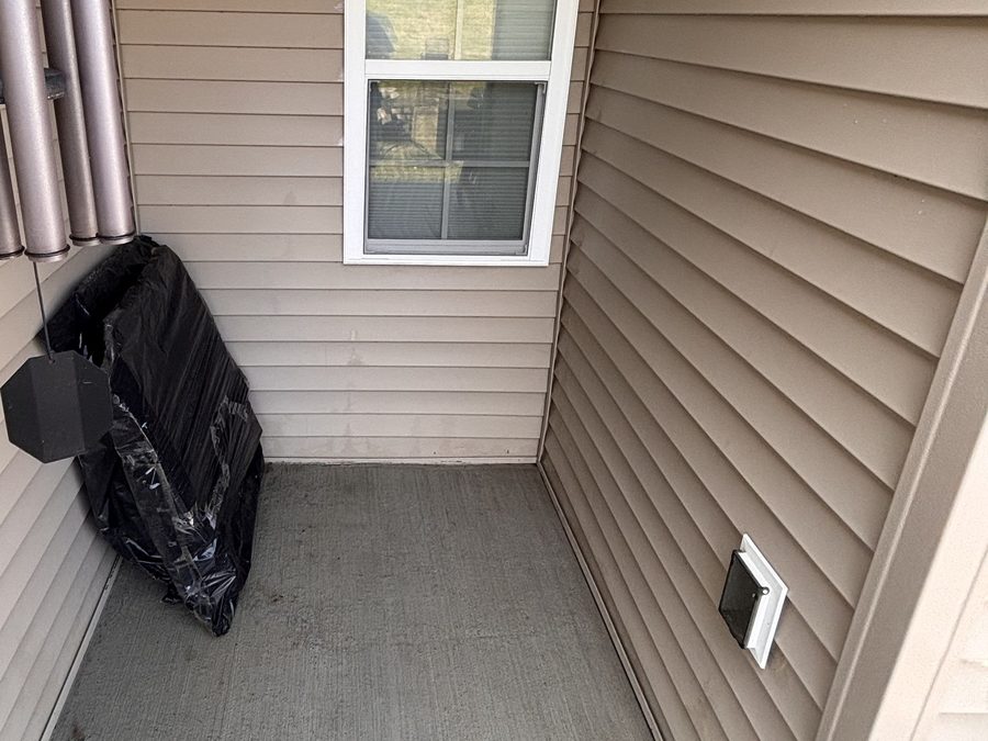 The same covered porch after cleaning, with clear concrete and freshly washed vinyl siding