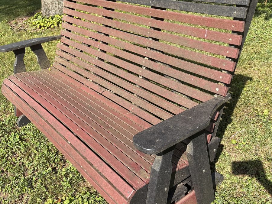 A poly outdoor bench before cleaning, faded and chalky with grime worked into the slats